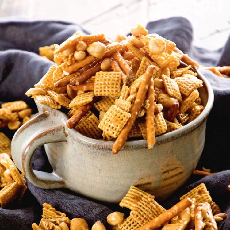 A large mug of caramel chex mix spilling out onto a kitchen towel