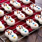 Nutter butter snowman cookies on a cooling rack over a red towel