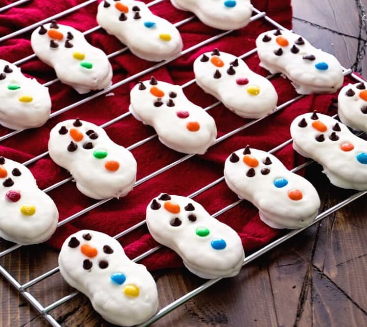 Nutter butter snowman cookies on a cooling rack over a red towel