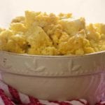 A white bowl of oven baked scrambled eggs sitting on a red and white kitchen towel