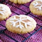 Snowflake snickerdoodle cookies on a cooling rack over a red towel