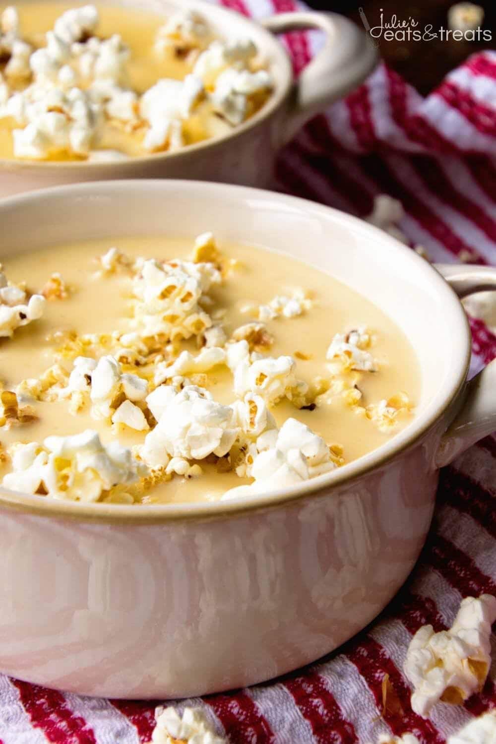 Cream colored crock bowl with beer cheese soup and popcorn in it.