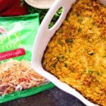 Cheesy chicken hash brown casserole in a white baking dish next to a bag of simply potatoes hash browns