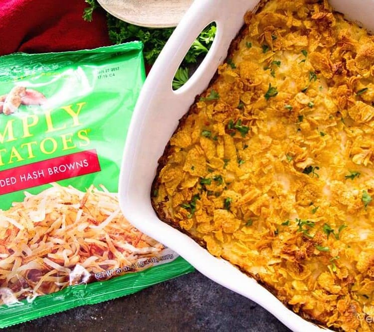 Cheesy chicken hash brown casserole in a white baking dish next to a bag of simply potatoes hash browns