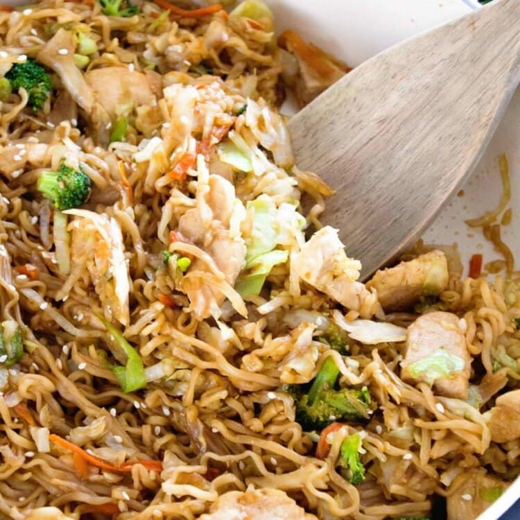 Chicken ramen stir fry in a skillet pan with a wood spatula