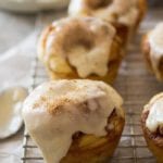 Cinnamon roll muffins with icing on top sitting on a wire cooling rack