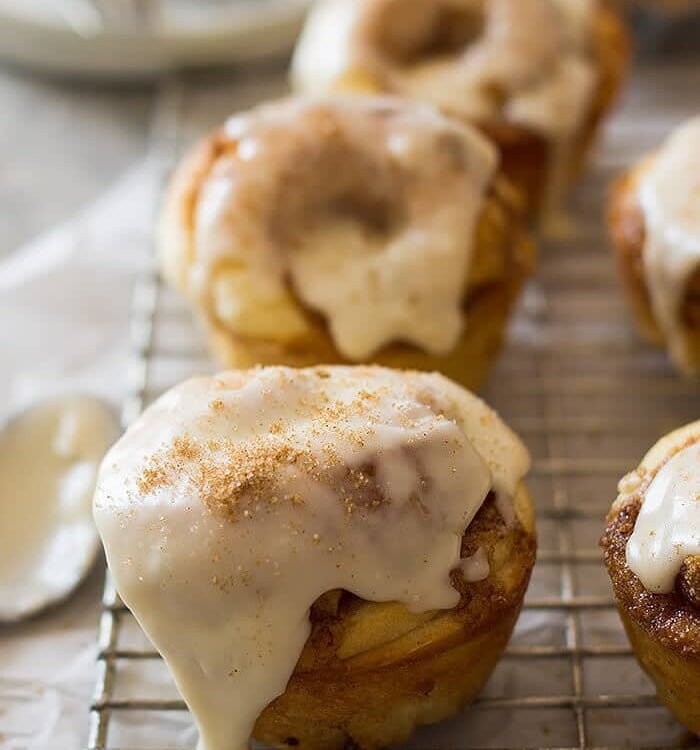 Cinnamon roll muffins with icing on top sitting on a wire cooling rack