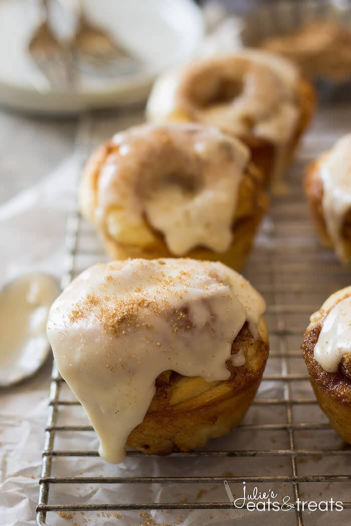 A cooling rack with frosted muffins on it.