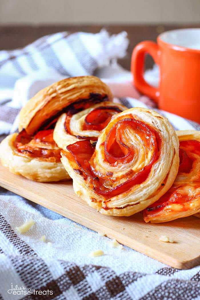 Puff Pastry Appetizers - Bacon Pinwheels with Cheddar sitting on a wooden cutting board.