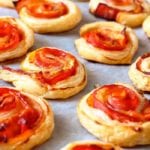 Puff pastry bacon pinwheels with cheddar cheese on parchment paper on a baking sheet