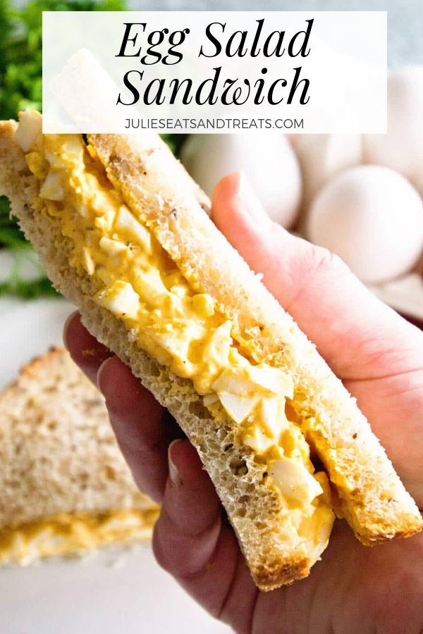 Hand holding an egg salad sandwich triangle