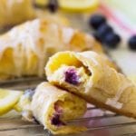 Lemon blueberry cheese cake crescent rolls on a white cooling rack with blueberries and lemon slices