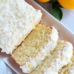 A partially sliced lemon and coconut loaf cake on a white tray