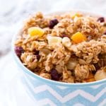 A blue and white chevron bowl of tropical coconut granola sitting on a white plate