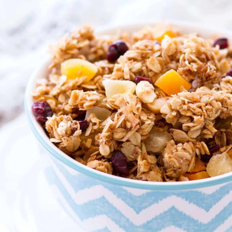 A blue and white chevron bowl of tropical coconut granola sitting on a white plate