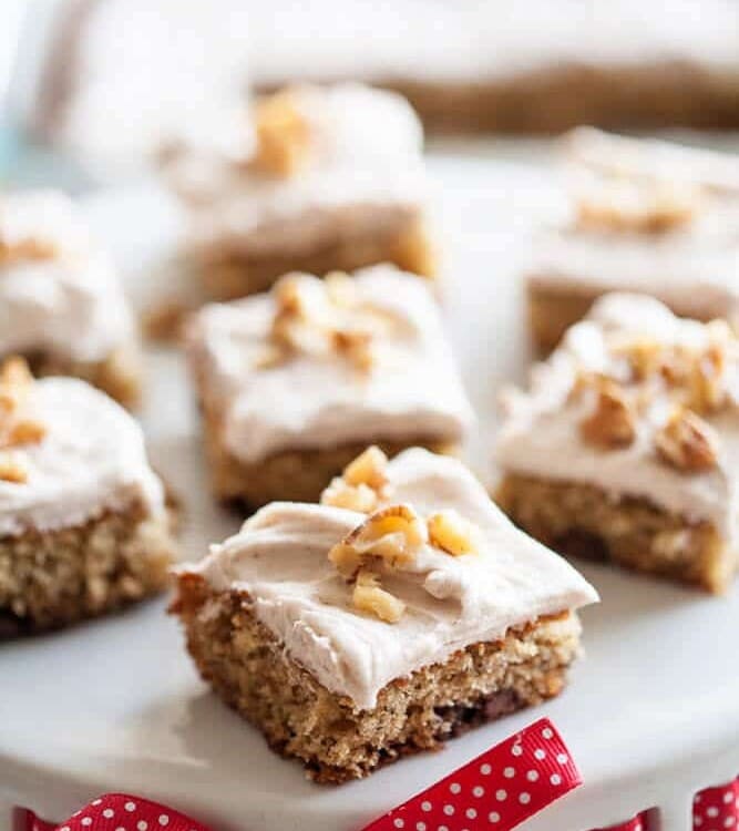 Banana nut bars on a white cake stand with a red ribbon around the base