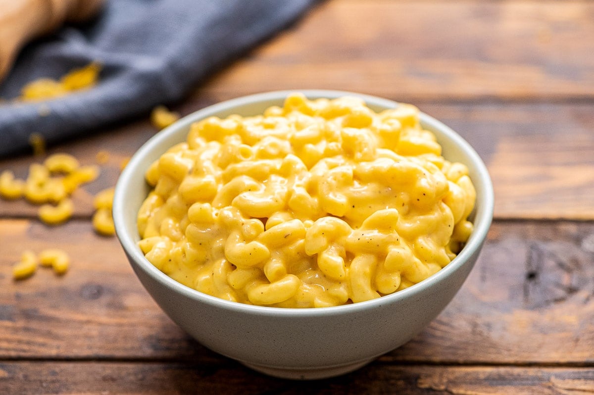 Bowl full of creamy mac and cheese on a wooden background.