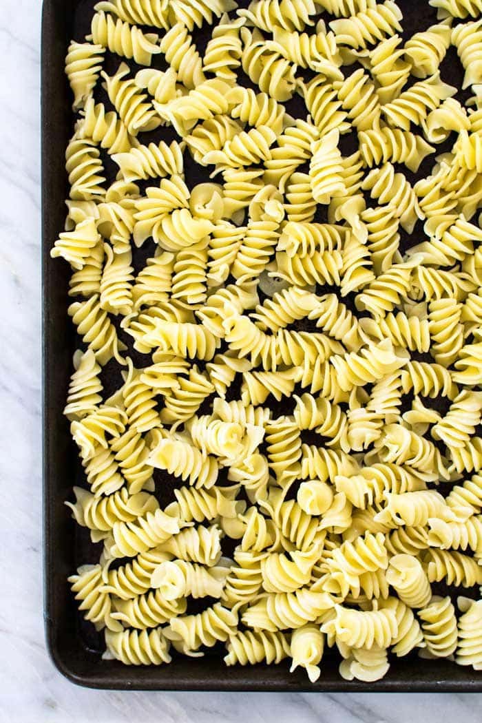 Sheet pan filled with fusilli pasta on a marble background