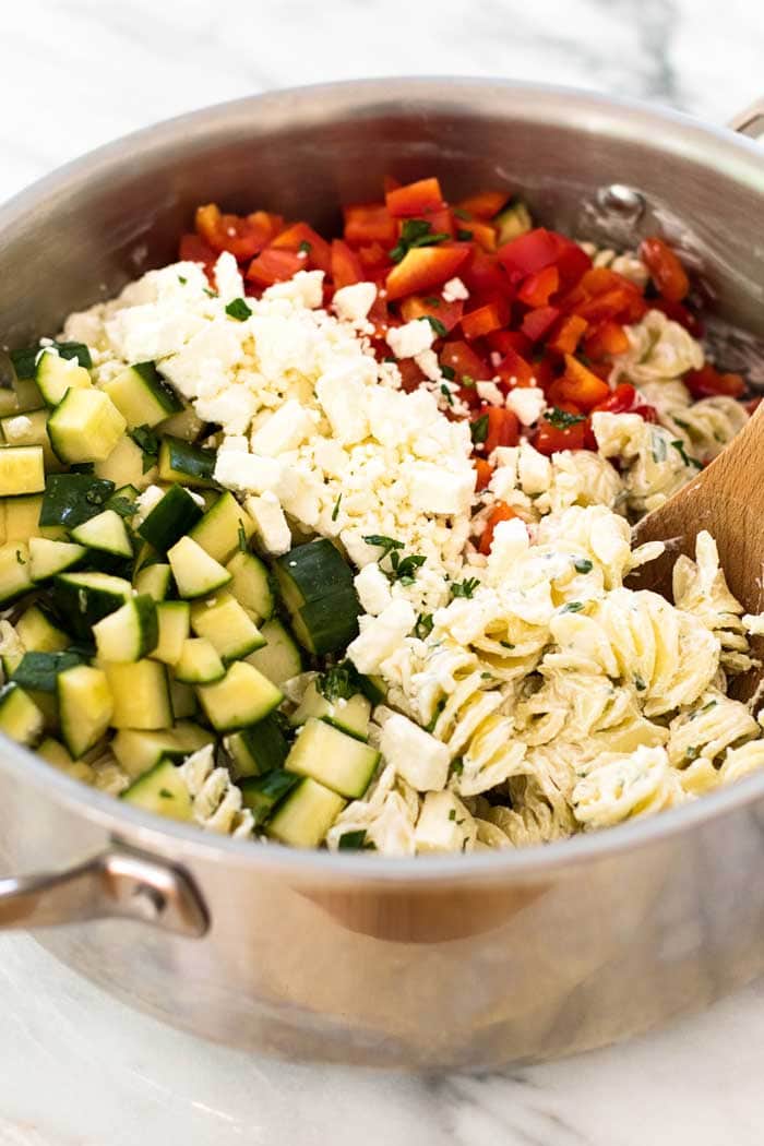 All the ingredients for this cold pasta salad recipe; Bell Pepper, Cucumber, Pasta and Topped with a Creamy Yogurt Dressing in a large bowl ready to be mixed.