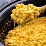Slow Cooker Mac and Cheese being scooped out of slow cooker with wooden spoon