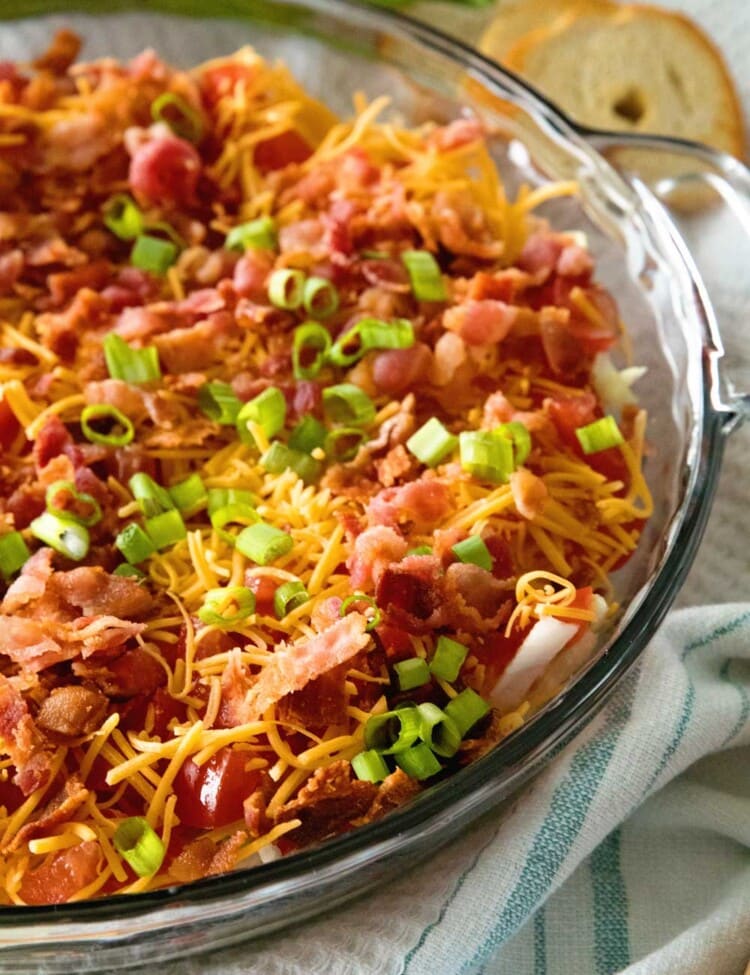 Easy BLT dip in a clear glass pie plate sitting on a white kitchen towel