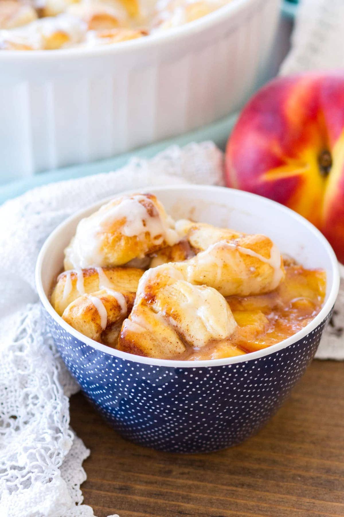 This Easy Cinnamon Roll Peach Cobbler is made with fresh peaches, sweet spices, and pre-made cinnamon roll dough. The final component of this cinnamon roll peach cobbler recipe is a sweet vanilla glaze, making this a quick and easy summer dessert! 