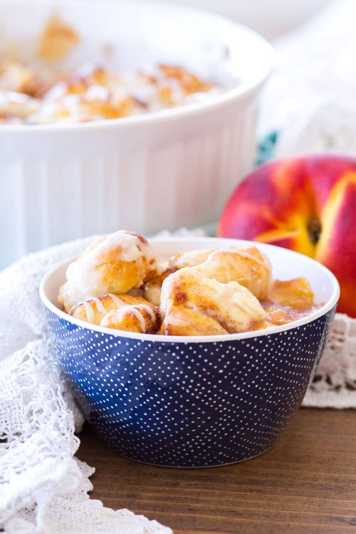 This Easy Cinnamon Roll Peach Cobbler is made with fresh peaches, sweet spices, and pre-made cinnamon roll dough. The final component of this cinnamon roll peach cobbler recipe is a sweet vanilla glaze, making this a quick and easy summer dessert! 