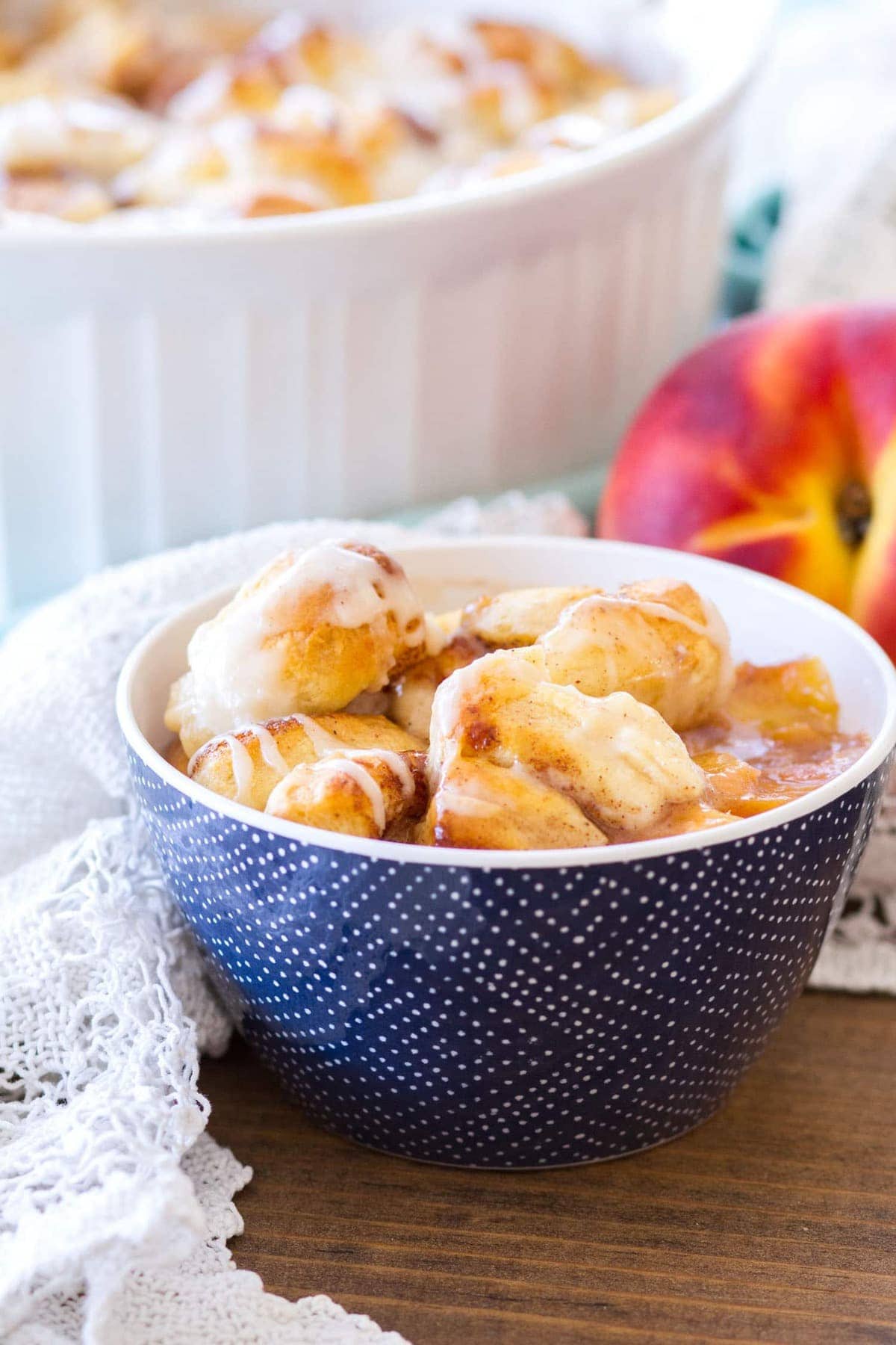 This Easy Cinnamon Roll Peach Cobbler is made with fresh peaches, sweet spices, and pre-made cinnamon roll dough. The final component of this cinnamon roll peach cobbler recipe is a sweet vanilla glaze, making this a quick and easy summer dessert! 