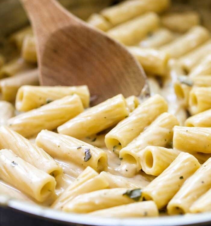 Wooden Spoon stirring Creamy Pesto Chicken Pasta in skillet