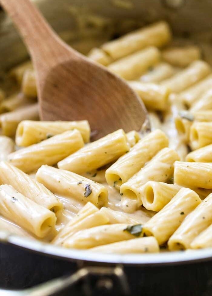 Wooden Spoon stirring Creamy Pesto Chicken Pasta in skillet