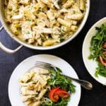 Creamy pesto chicken pasta in a pot and on a white plate with salad
