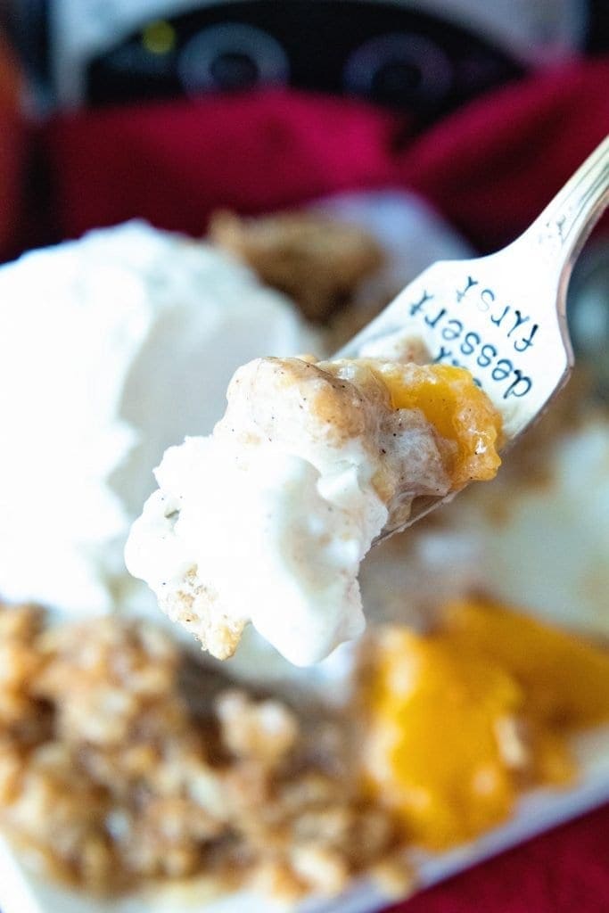 A fork full of crisp that's topped with ice cream.