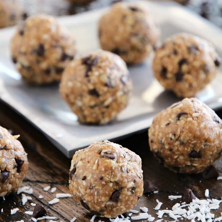 No bake chocolate chip energy bites on a table and on a silver plate sprinkled with coconut flakes and mini chocolate chips