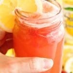 hand holding mason jar full of sparkling strawberry lemonade with a lemon slice