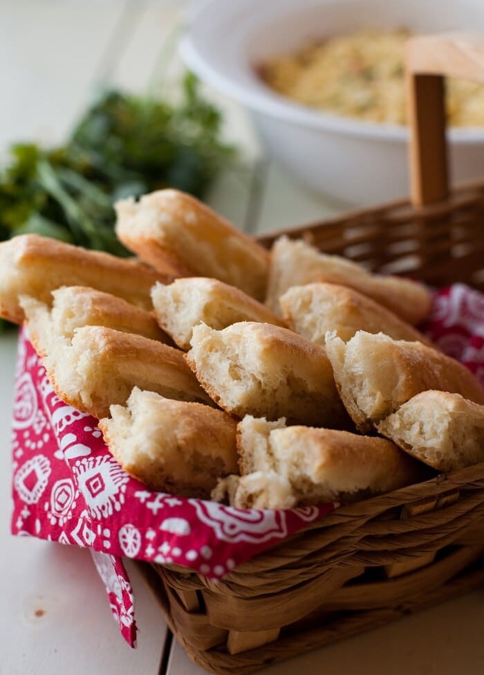 A dozen breadsticks on a red cloth in a whicker basket