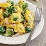 Broccoli tortellini on a white plate with a fork