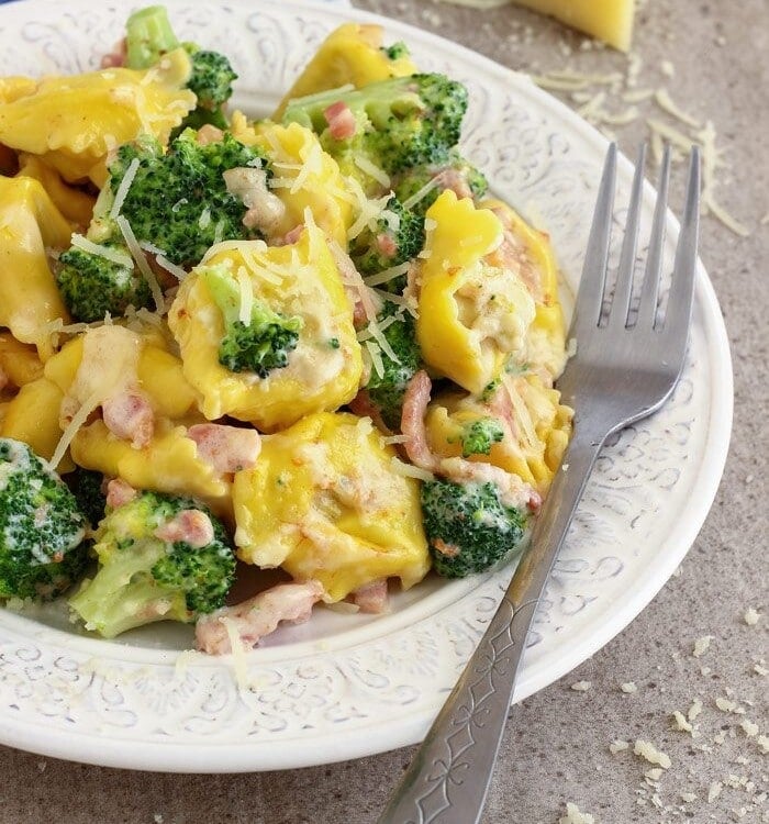 Broccoli tortellini on a white plate with a fork