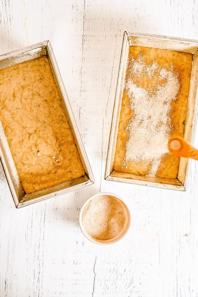 Two load pans with zucchini bread batter, one topped with cinnamon sugar mixture