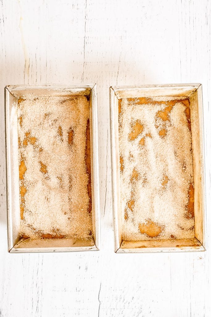 Overhead image of two loaf pans with zucchini bread batter in them topped with cinnamon sugar