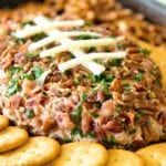 Cheesy bacon ranch football shaped cheese ball surrounded by ritz crackers and pretzels