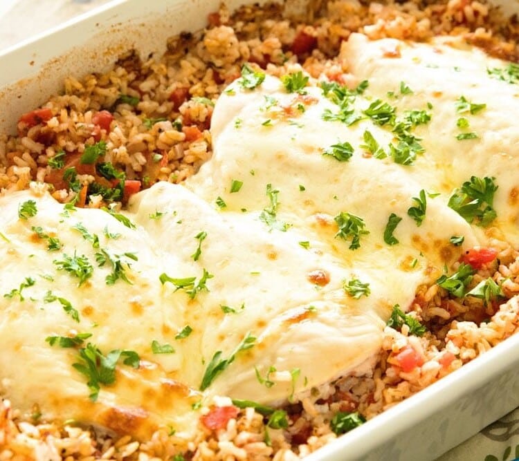 Cheesy Italian chicken and rice casserole in a white baking dish topped with fresh parsley