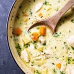 Chicken pot pie soup in a pot with a wooden spoon