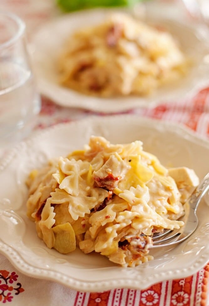 Two white plates with sun dried tomato and artichoke pasta