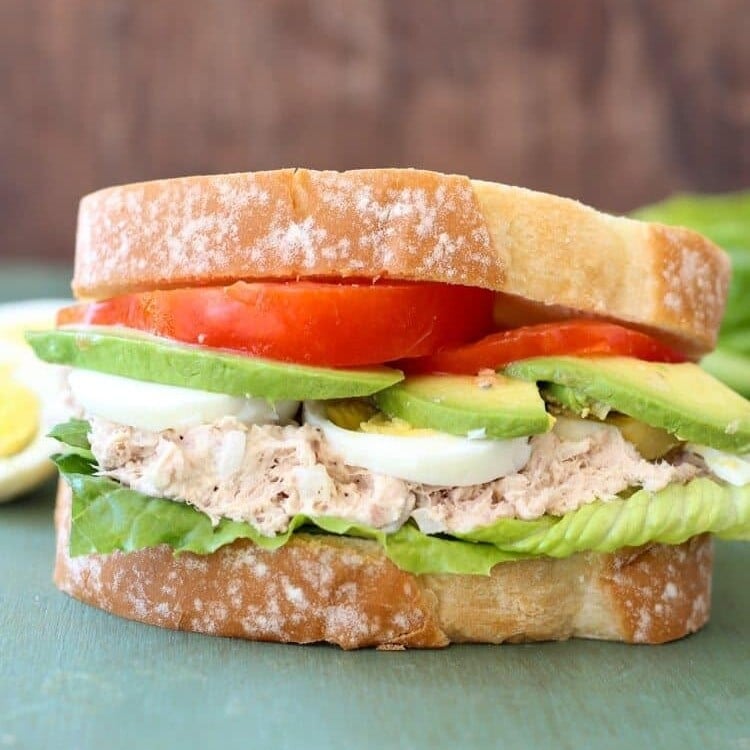 Tuna avocado sandwich with hard boiled eggs, lettuce, and tomato