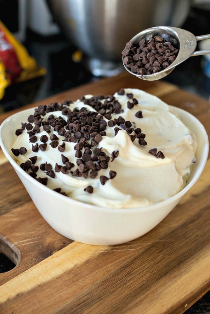 Mini chocolate chips being sprinkled on cannoli dip