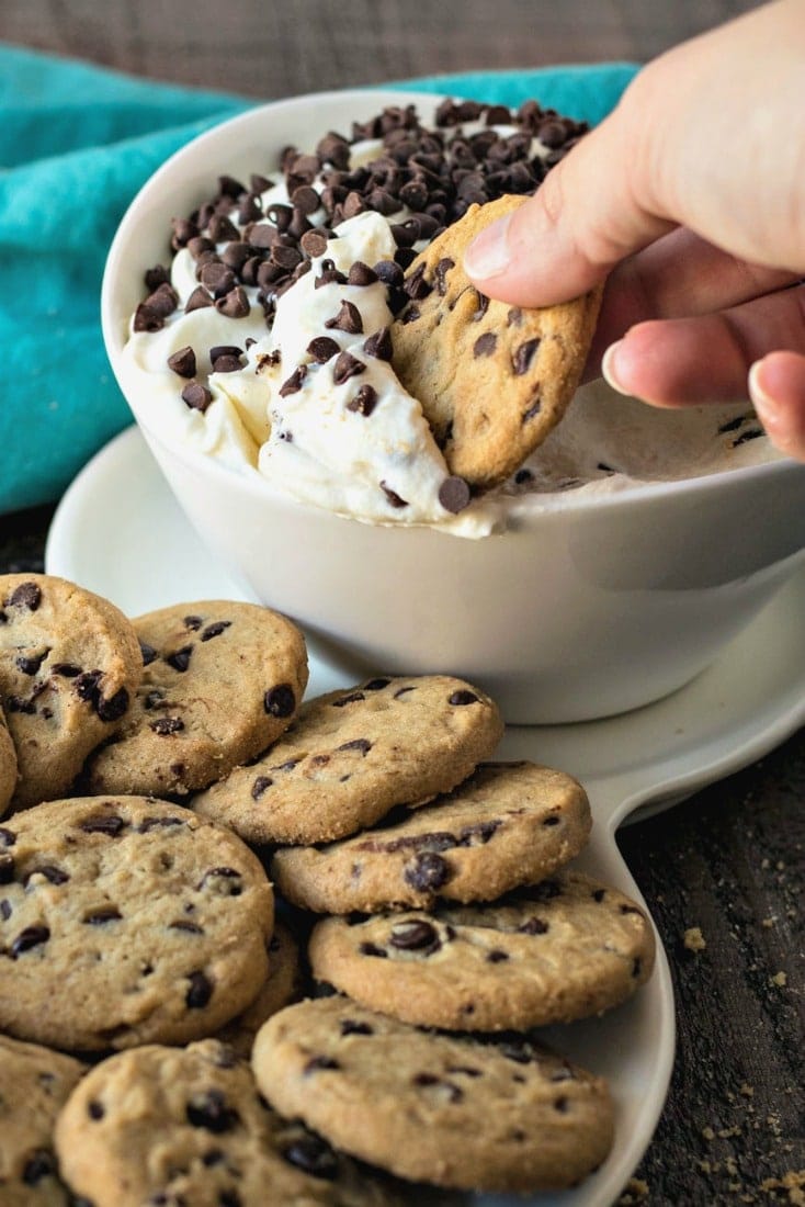 Chocolate chip cookie being dipped into cannoli dip