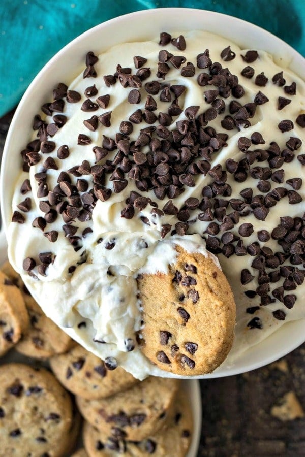 Cannoli dip in a white bowl covered in mini chocolate chips with a cookie in it