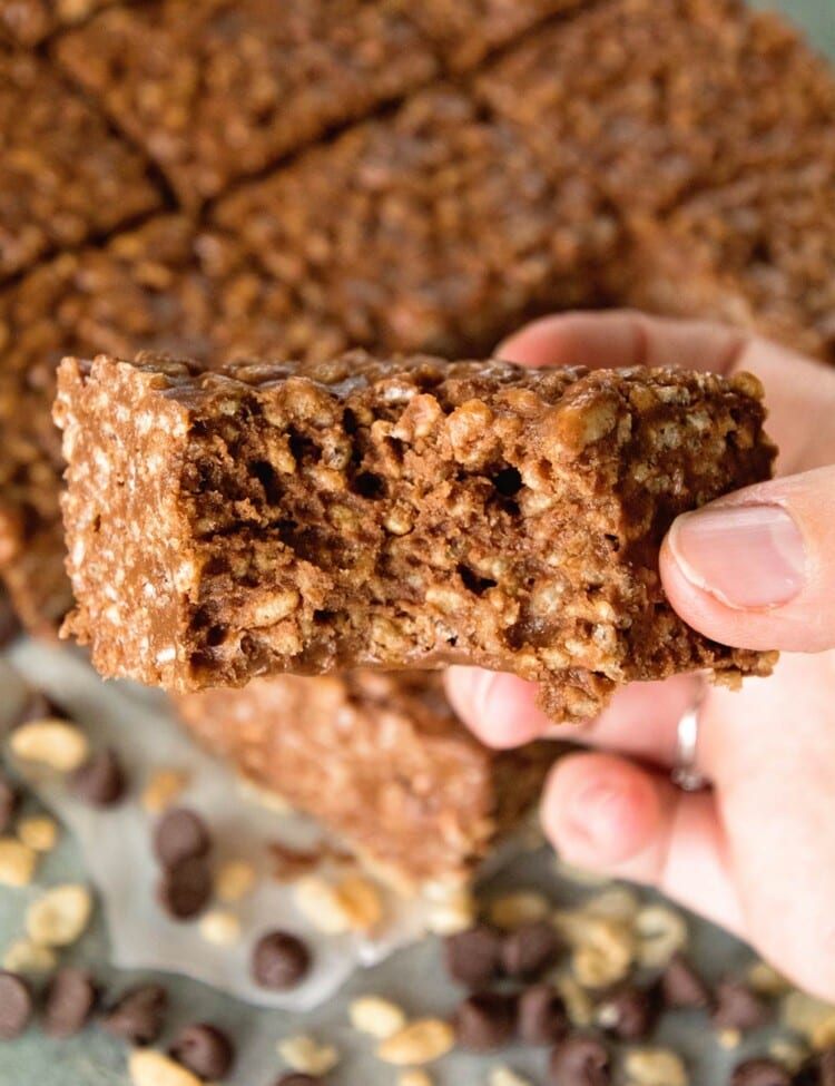 Hand holding a chocolate peanut butter rice krispies bar with a bite out of it