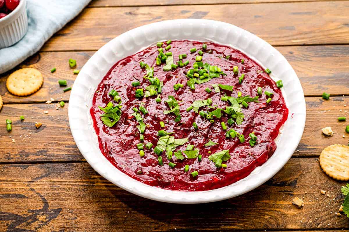 White pie plate with cranberry dip in it on a wooden background