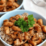 Two blue bowls of crock pot chicken teriyaki on rice